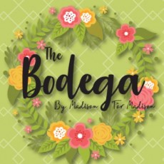 Green background with wreath of pink and yellow flowers with "The bodega" in the middle in black lettering