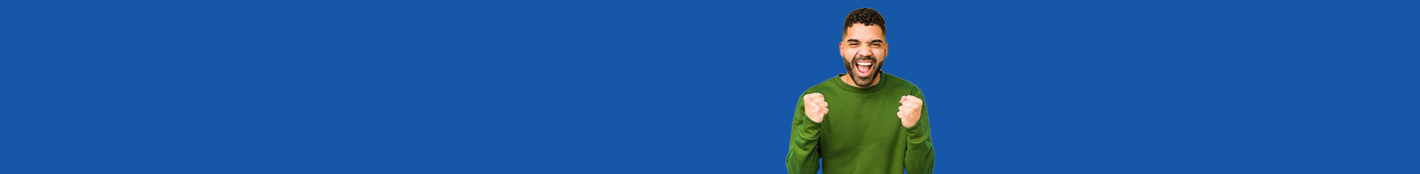 young man in green sweater clinching fists in excitement with bold blue background